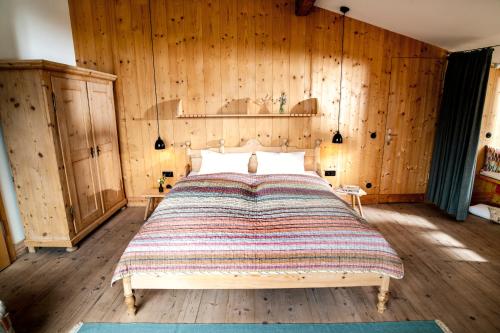a bedroom with a bed with a wooden wall at Tannerhof - Mein Versteck in den Bergen in Bayrischzell