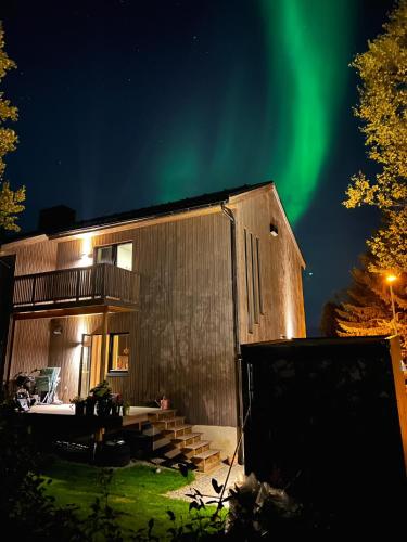 a house with the green northern lights in the sky at Central apartment in Tromsø