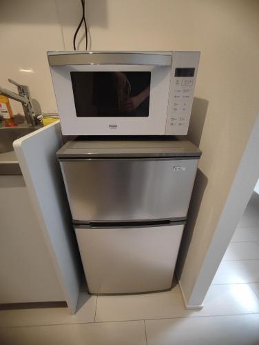 a microwave oven sitting on top of a refrigerator at 201Room,7-minute walk from Uguisudani Station located on the 2nd floor of an apartment-style building Twin room No elevator in Tokyo