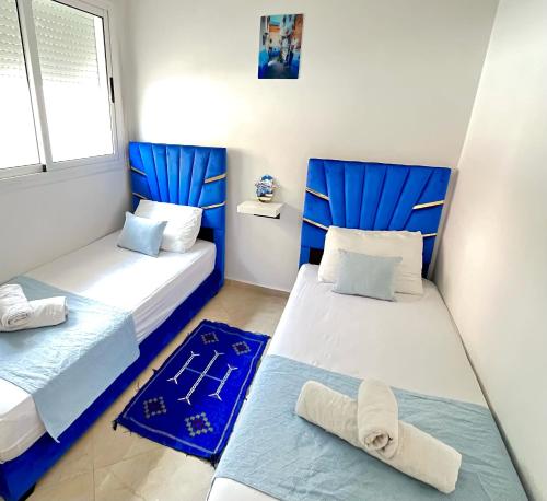two beds in a room with blue and white at Chauen White Pearl Apartments in Chefchaouene