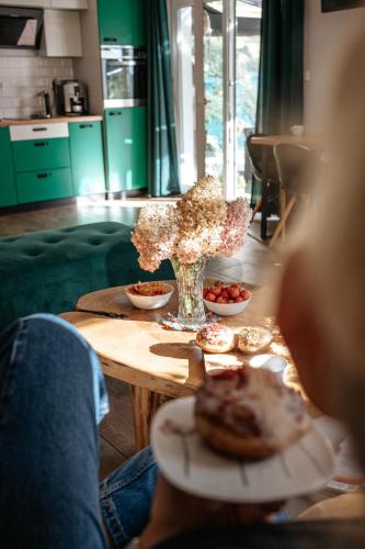 a table with a vase of flowers and a plate of food at Domek Pierwiosnek Ustroń - cisza, las, balia i totalny relaks - Ucieknij od zgiełku i poczuj spokój natury in Ustroń
