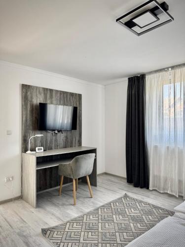 a hotel room with a desk and a television at Relax House El Passo in Târgu-Mureş