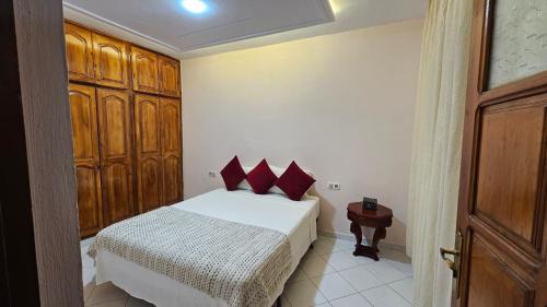 a bedroom with a bed with red pillows and a table at Dar Boujida in Larache