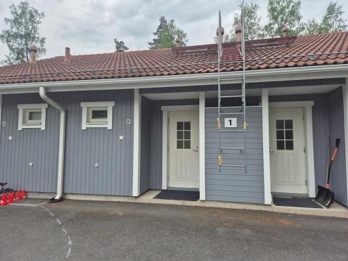 Un garaje gris con puertas blancas y techo rojo. en Rivitalo kylpylän lähellä, en Kilvakkala