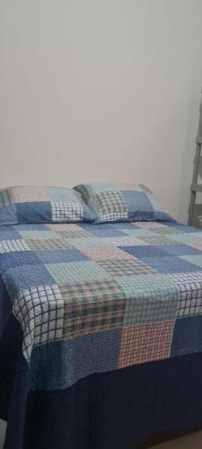 Una cama con una manta a cuadros. en Apartamentos da Casa Azul, en Trancoso