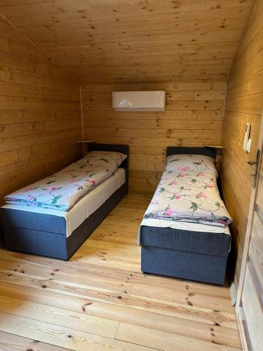 two beds in a small room with wooden walls at SuliCamp Kompleks Wypoczynkowy in Sulistrowice
