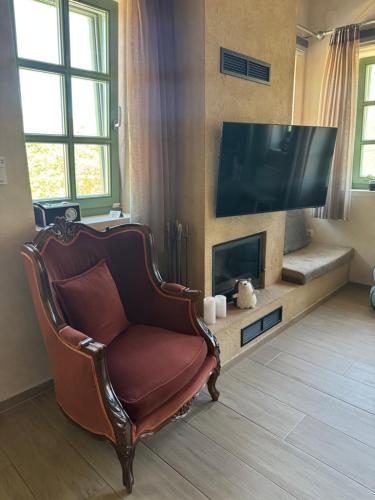 a living room with a chair and a flat screen tv at Aristi boutique stonehouse with attic in Aristi
