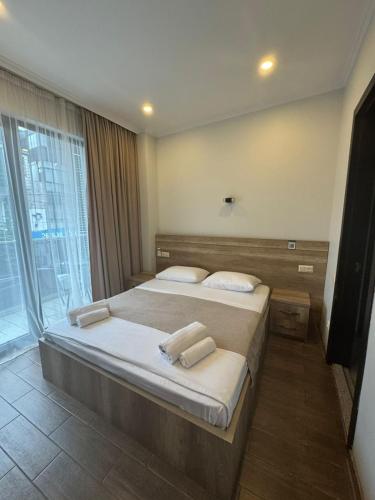 a bedroom with a large bed and a large window at Hotel Corner Batumi in Batumi
