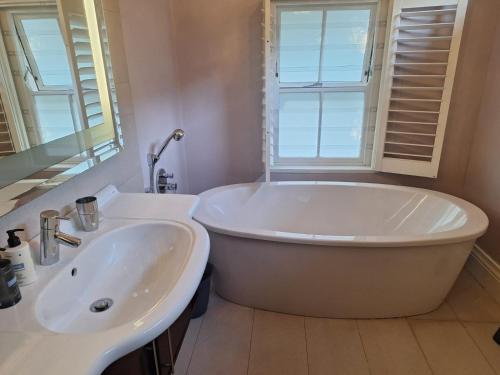 开普敦Bishopsfield Guesthouse Rondebosch的带白色浴缸和水槽的浴室