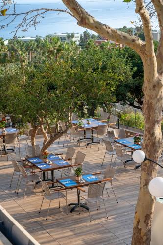 a row of tables and chairs on a patio with trees at Royal & Imperial Belvedere Resort in Hersonissos