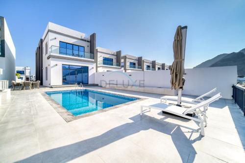 a villa with a swimming pool and a house at Luxurious 4-Bedroom Villa with Assistant Room and Private Pool in Al Dana Island, Fujairah by Deluxe Holiday Homes in Fujairah