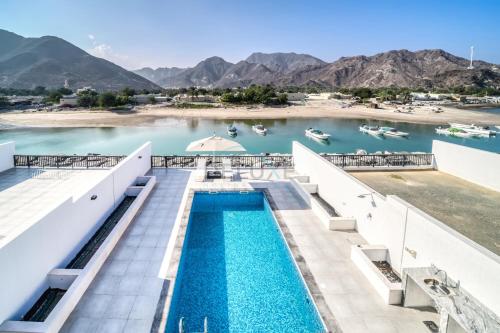 a view of the infinity pool at a resort with boats in the water at Luxurious 4-Bedroom Villa with Assistant Room and Private Pool in Al Dana Island, Fujairah by Deluxe Holiday Homes in Fujairah