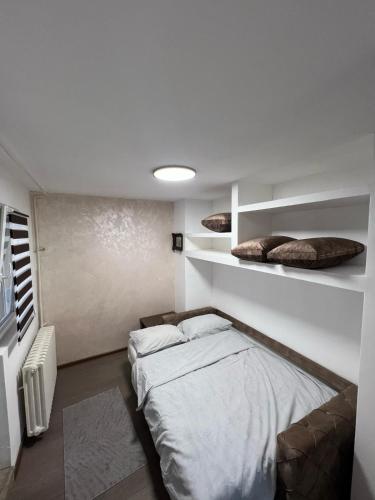 a bedroom with a bed and shelves in it at Apartman Stefan in Novi Sad