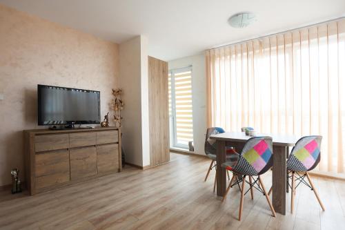 a living room with a table with chairs and a tv at Апартамент за гости 2 Тракия Плаза in Shumen