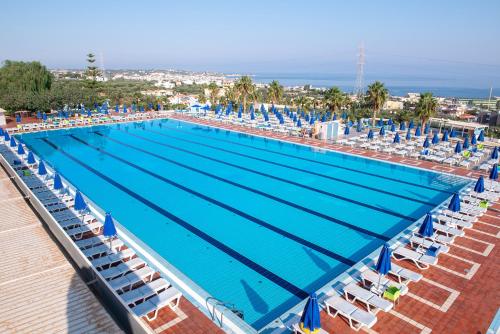 a large swimming pool with chairs and the ocean at Royal & Imperial Belvedere Resort in Hersonissos