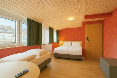 a hotel room with two beds and a remote control at Hotel Hafner - Self Check-In in Stuttgart