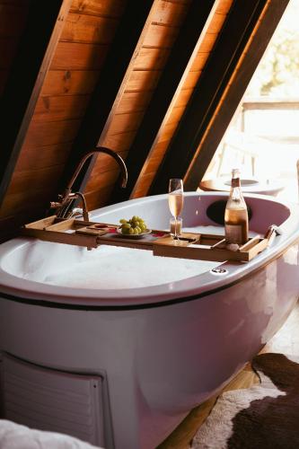 a bath tub with a table and a bottle and glasses at Chalet with Private Jacuzzi and View of the Jucu River in Domingos Martins