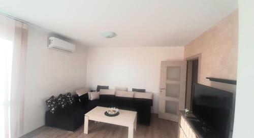 a living room with a black couch and a table at Апартамент за гости 2 Тракия Плаза in Shumen