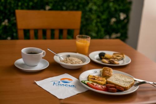 a table with plates of breakfast food and a cup of coffee at Hotel Riviera in Rhodes Town