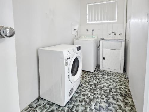 a white washer and dryer in a bathroom at Golden Sands Motor Inn in Forster