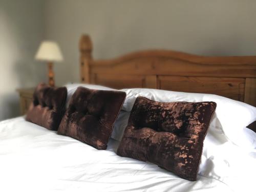 a white bed with two brown pillows on it at Littledean House Hotel in Cinderford