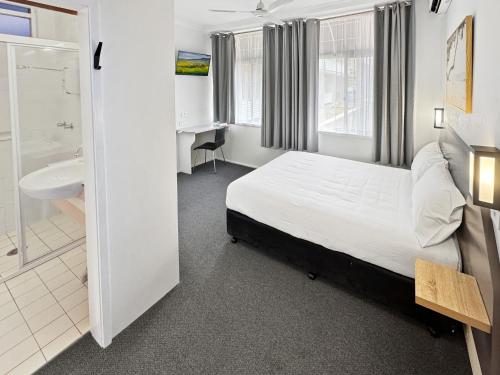 a bedroom with a bed and a bathroom with a sink at Golden Sands Motor Inn in Forster