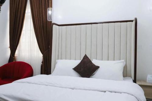 a bedroom with two beds and a red chair at Hometime Utako in Abuja