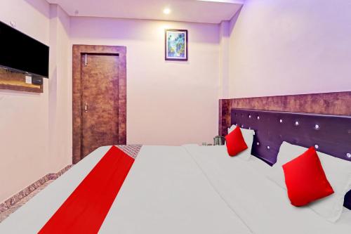 a bedroom with a large bed with red pillows at Hotel O Saharsh Hotel in Patna