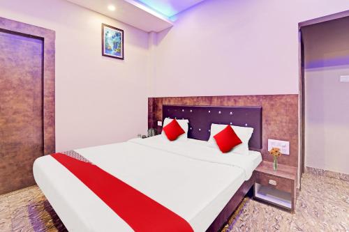 a bedroom with a large bed with red pillows at Hotel O Saharsh Hotel in Patna