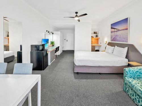a bedroom with a bed and a living room at Golden Sands Motor Inn in Forster