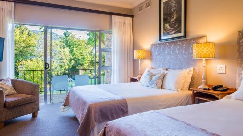 a hotel room with two beds and a balcony at ANEW Resort Ingeli Forest Kokstad in Kokstad