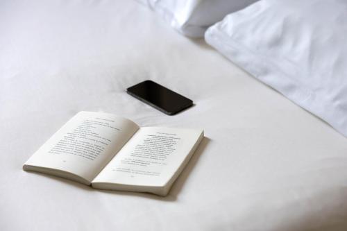 a book and a cell phone on a bed at Ibis Budget Albi Centre in Albi