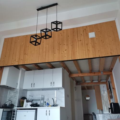 a kitchen with white cabinets and a wooden ceiling at Zenith Center Apartment in Ohrid