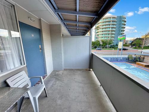 a balcony with a table and chairs and a swimming pool at Golden Sands Motor Inn in Forster