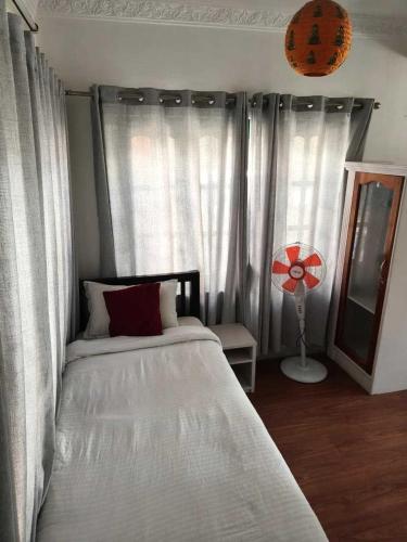 a bedroom with a bed and a window with a fan at Casablanca Nepal at Tours By Nayan in Kathmandu
