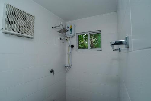 Baño blanco con ducha y ventana en Mist of Sinharaja, en Galle