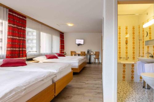 a hotel room with two beds and a bathroom at Hostel Casa Franco in St. Moritz