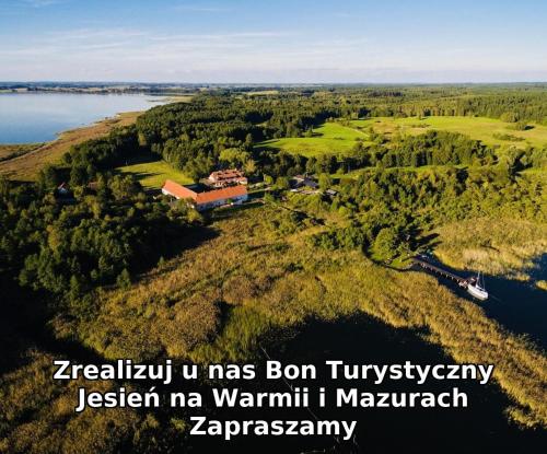 ミコワイキにあるFolwark Łuknajno nad Jeziorem Śniardwy Gospoda Dziedzictwo Kulinarne Warmia-Mazuryの湖畔の丘の上の家屋