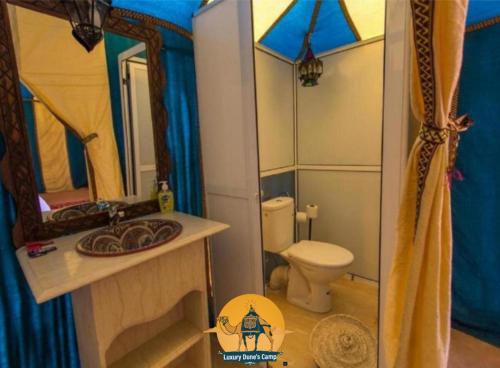 a bathroom with a toilet and a sink and a mirror at Luxury Dune's Camp in Merzouga