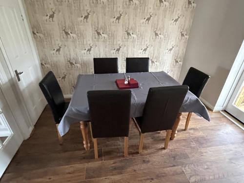 a dining room table with black chairs and a table cloth at Quiet 3 bed semi with off street parking in Bingham