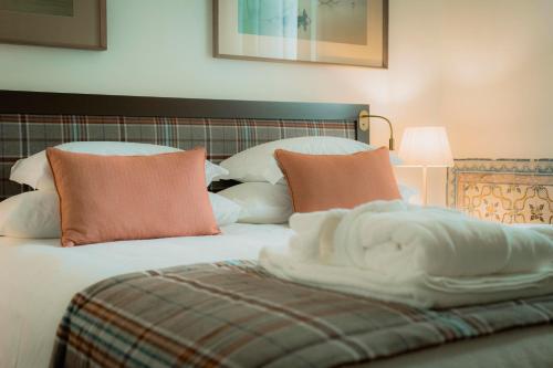 a bed with white sheets and orange pillows at Once Upon Lisboa in Lisbon