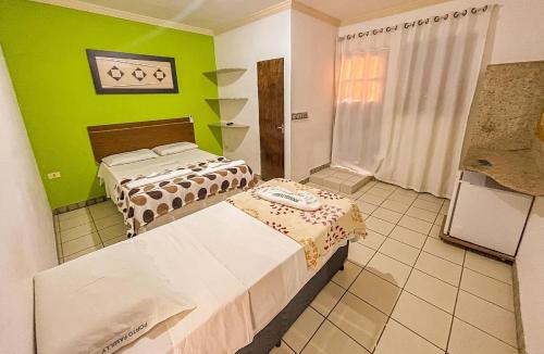 two beds in a room with a green wall at Pousada Familly Porto de Galinhas in Porto De Galinhas