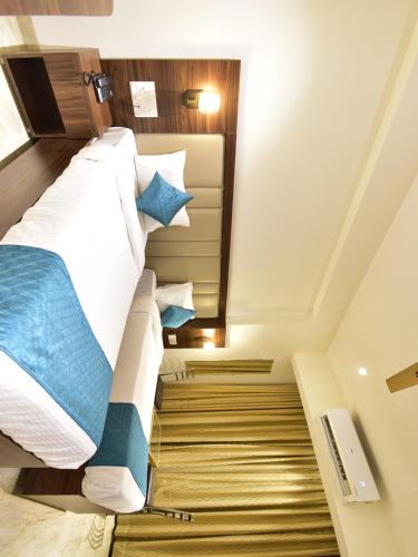 a bedroom with a large bed with blue pillows at Hotel Candor Amigo Airoli Mind Space in Navi Mumbai