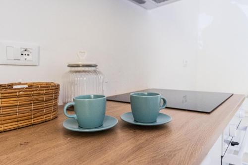two coffee cups sitting on a wooden table at Santa Maria Apartments in Forino