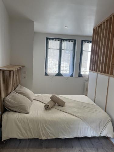 a bed in a white room with two windows at Charmant et Lumineux in Caussade