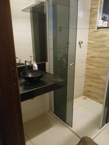 Un baño con lavabo y ducha de cristal. en Casa aconchegante, en Salto