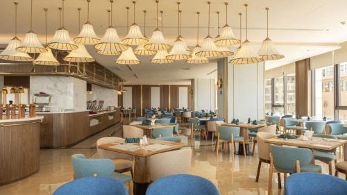 a restaurant with blue chairs and tables and chandeliers at Mandala Cham Bay Mui Ne in Ấp Nhơn Hòa