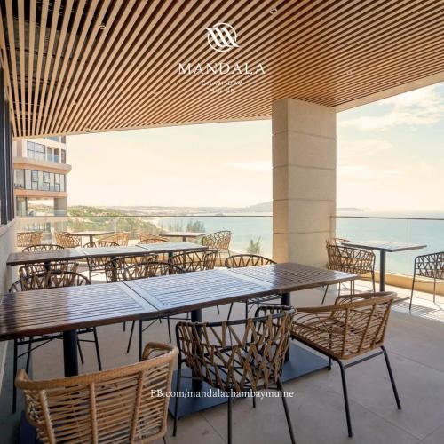 a restaurant with tables and chairs and a view of the ocean at Mandala Cham Bay Mui Ne in Ấp Nhơn Hòa