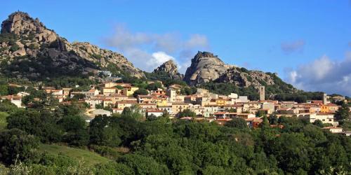 a village on a hill with mountains in the background at AbalabÀ - Gallura Retreat - Domo in Aggius