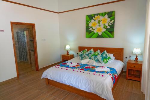 een slaapkamer met een bed en een schilderij aan de muur bij La Maison Figaro Guest House in La Réunion